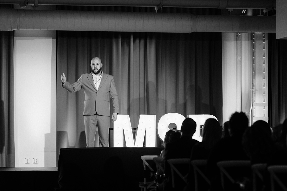 Steve Reuter on stage, arm raised, addressing an audience