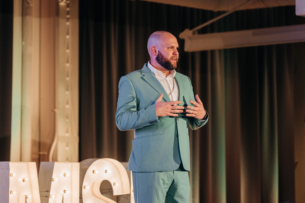 Steve Reuter mid-talk on stage, gesturing, at a DisruptHR event